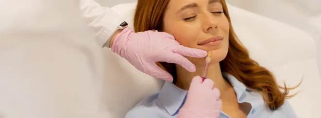 Woman receiving a lip filler injection in a clinic.
