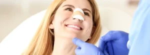 Rhinoplasty patient smiling with nasal splint on